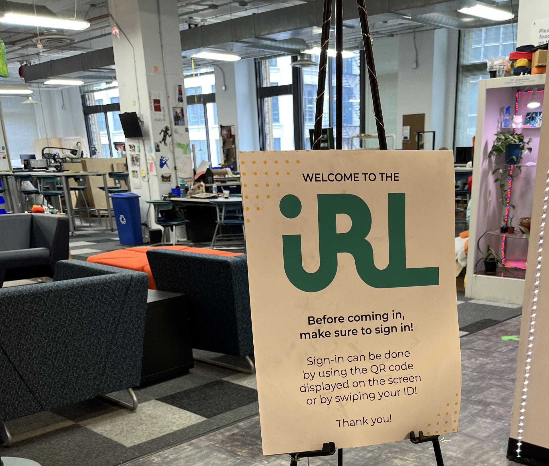 A sign that says “Welcome to IRL” at DePaul’s idea lab, showing comfy chairs, work spaces and the rest of DePaul’s loop campus space.
