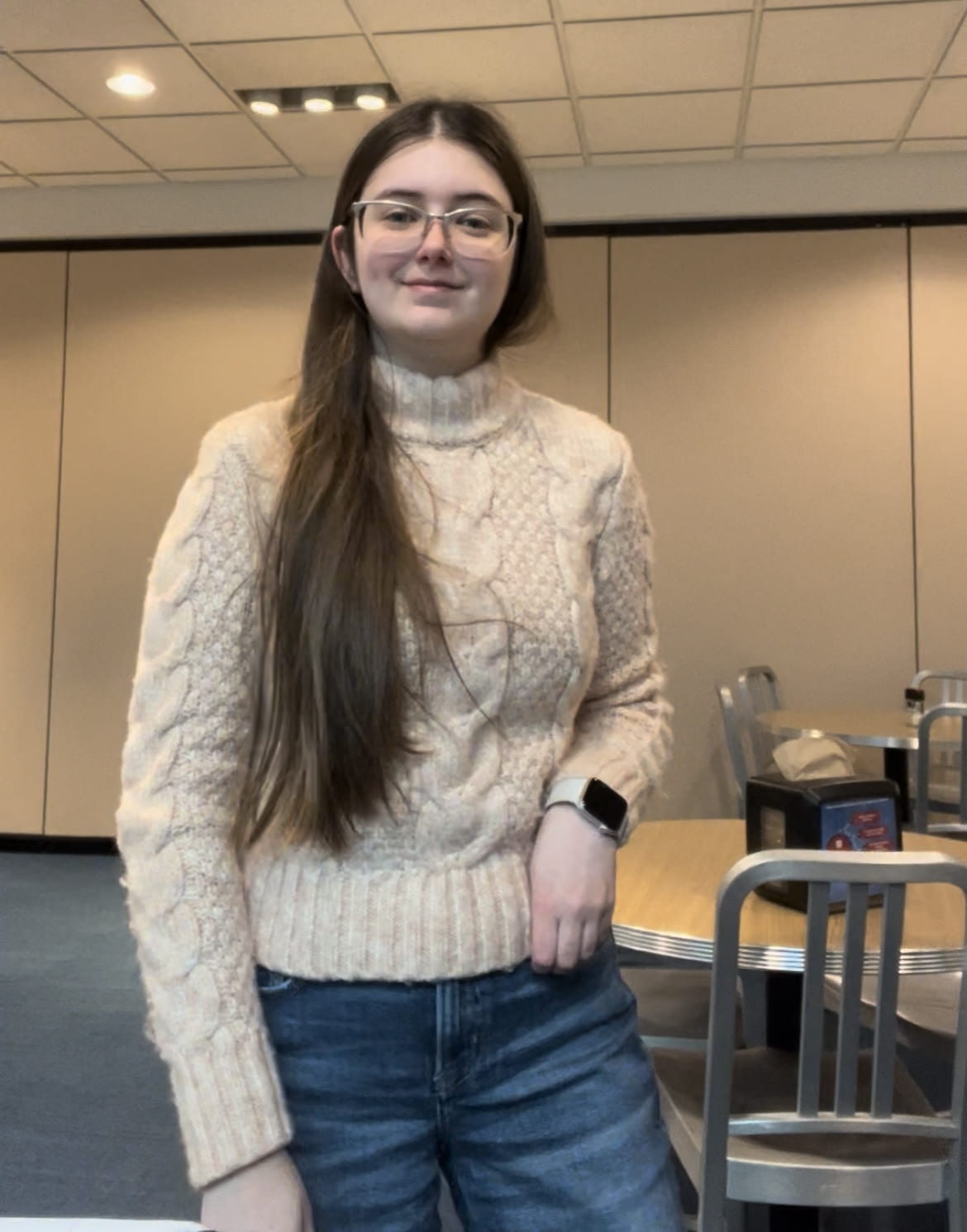 Sienna smiling in DePaul with a thick pink sweater on with blue jeans. 