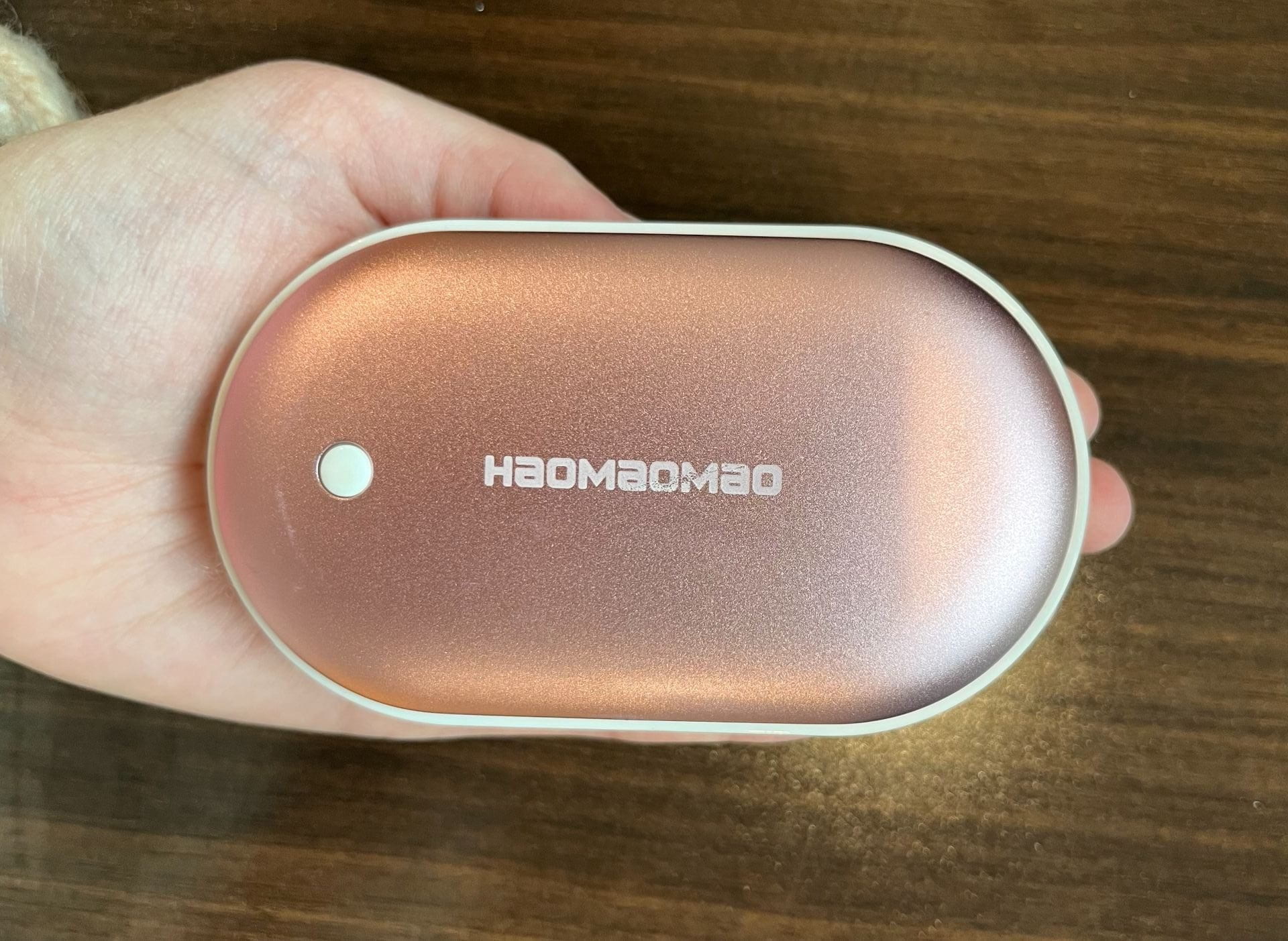 A pink circle handwarmer in a hand.