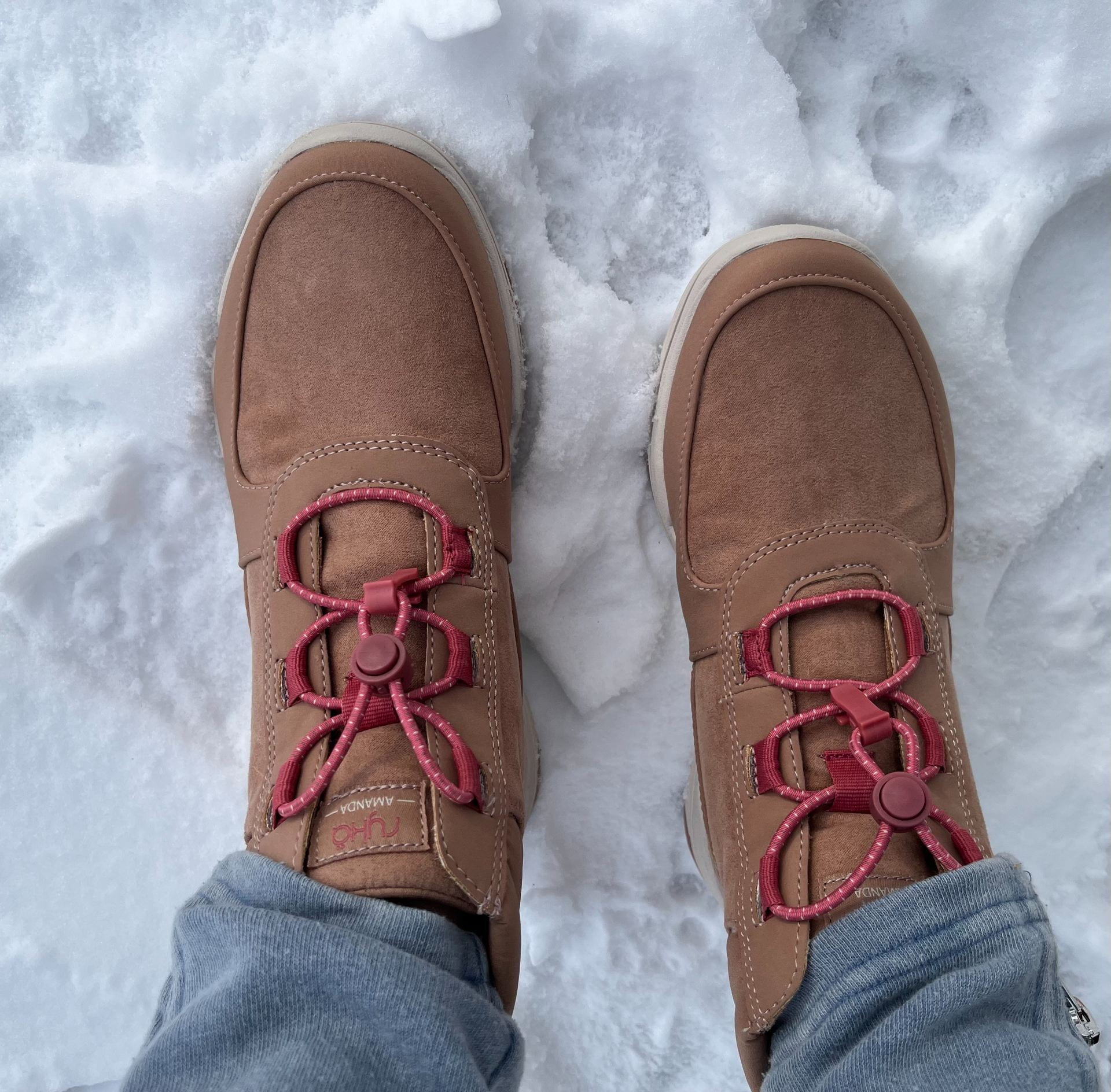 A pair of brown boots standing on snow