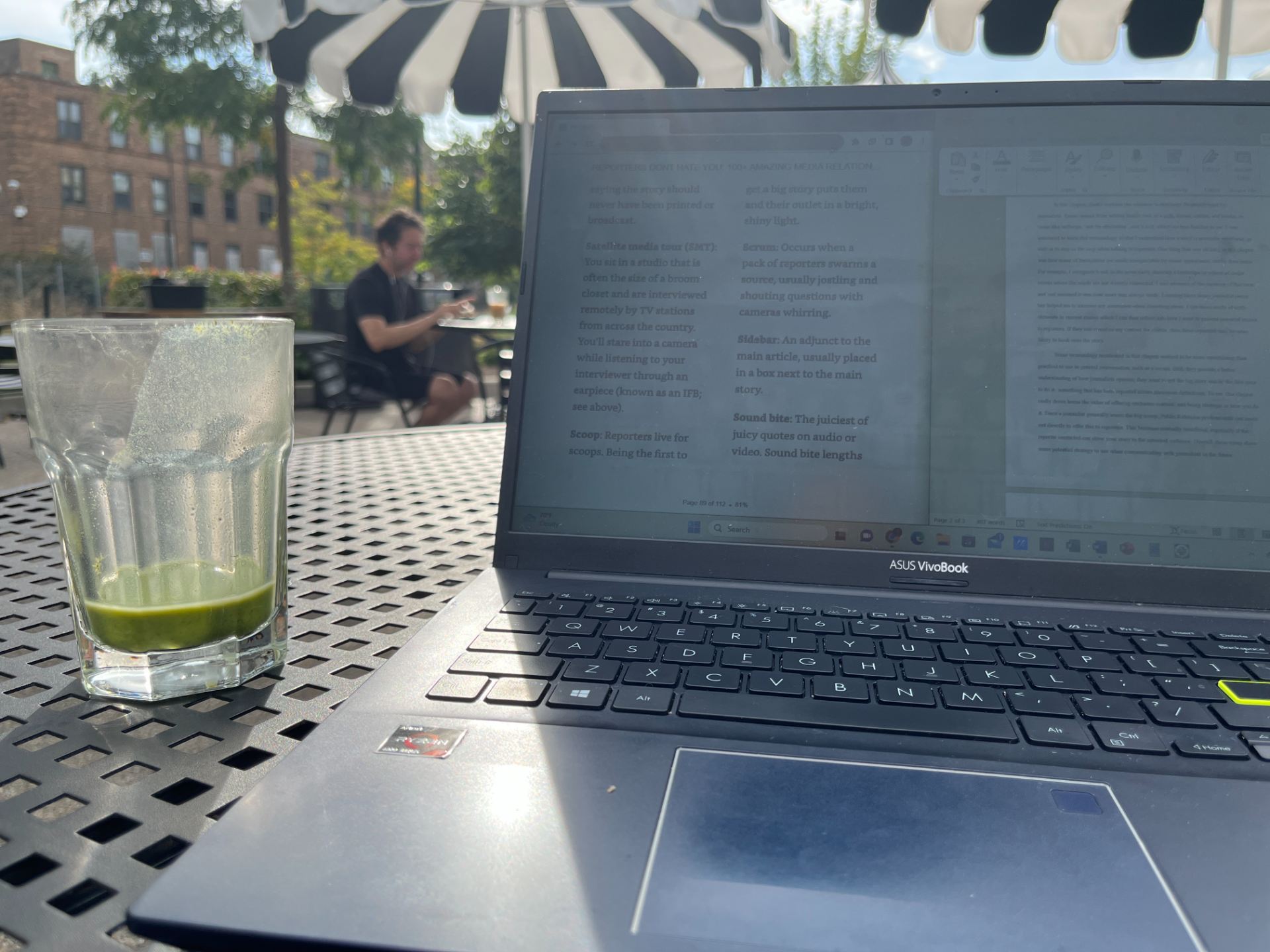 Laptop and empty glass of matcha showing student working on applications in an outdoor patio space