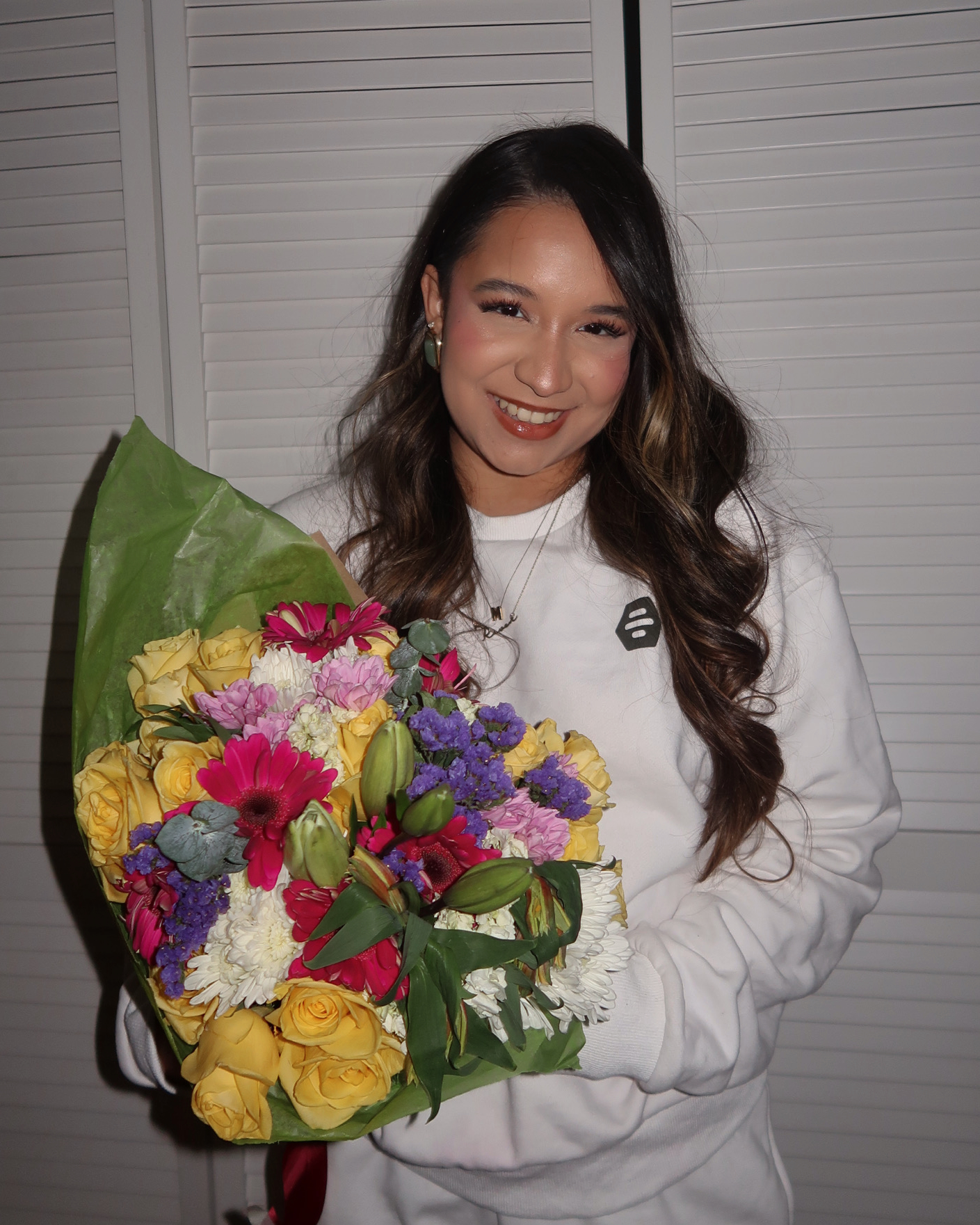 DeBlogger Marina wearing Bumble merch and holding a bouquet of assorted flowers.