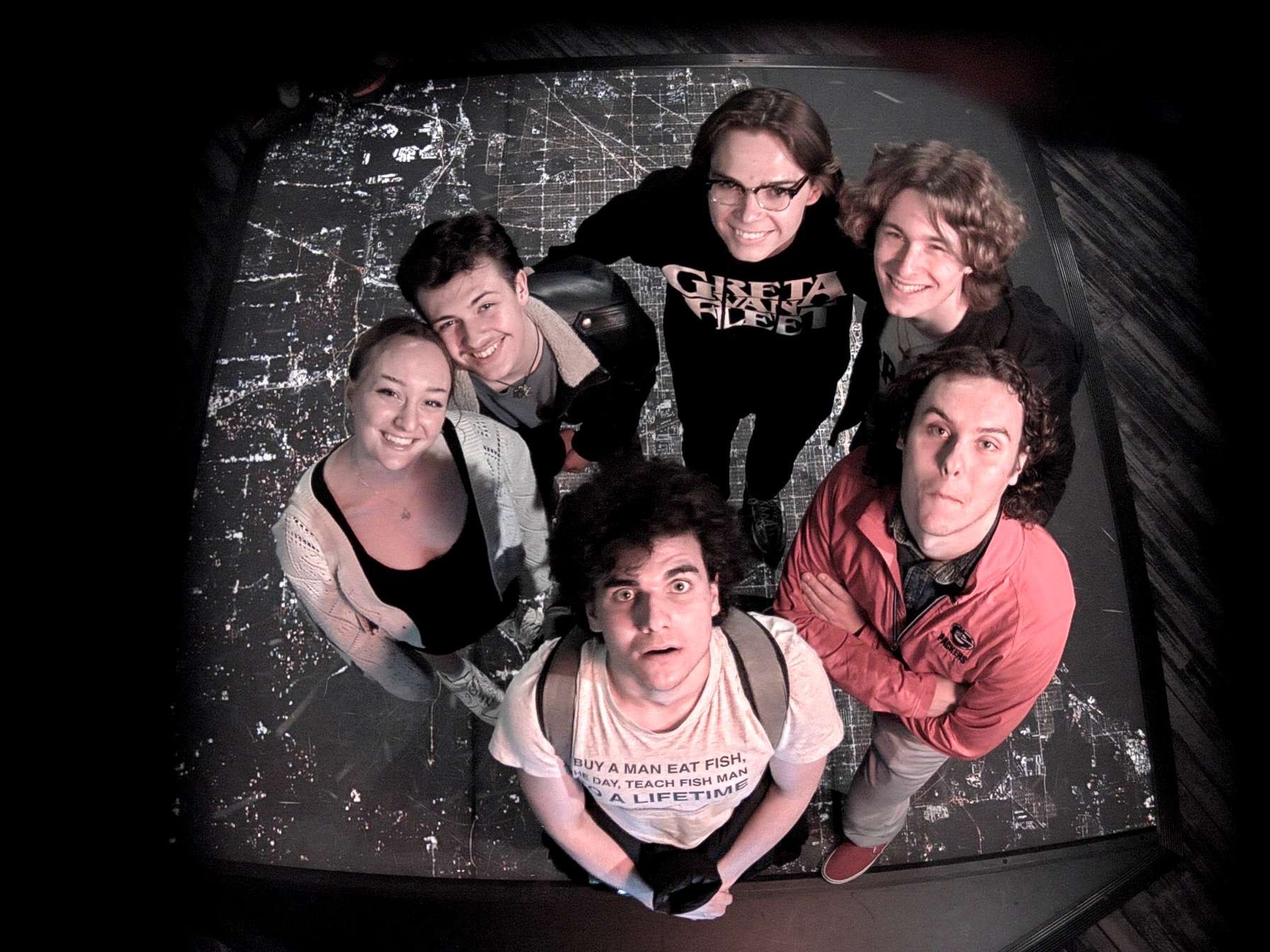 An overhead photo of a group of DePaul University students standing on a satellite view of Chicago at the Adler Planetarium.