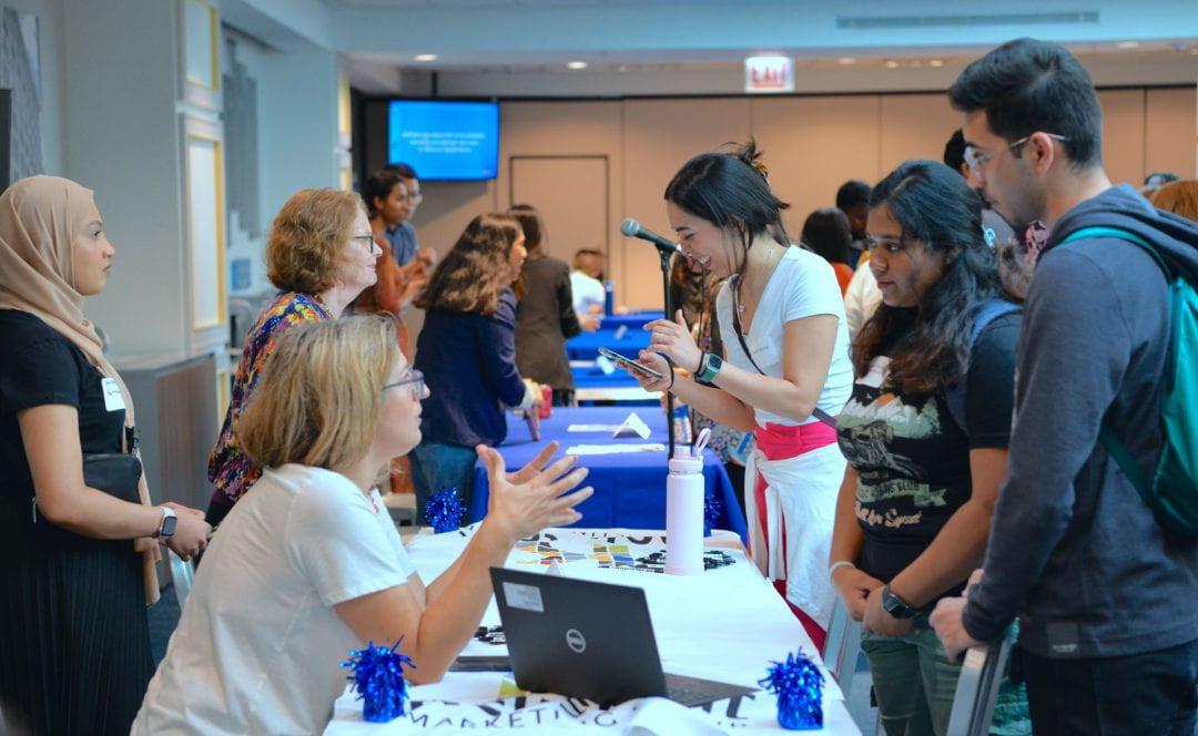 Students engaged in conversation with staff at an open house event